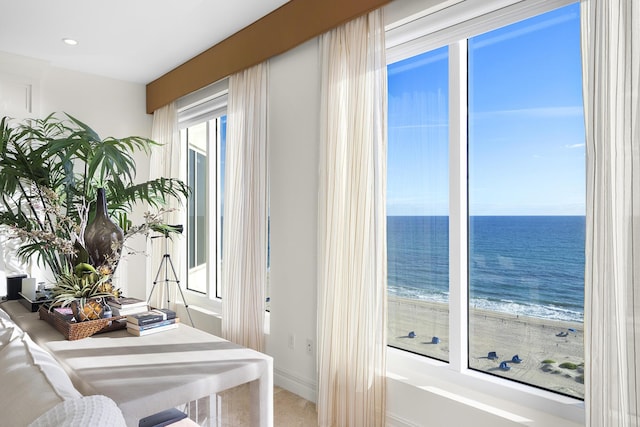 interior space with a water view, a wealth of natural light, and a beach view