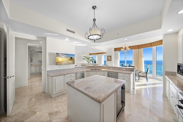 kitchen featuring a kitchen island, stainless steel dishwasher, kitchen peninsula, and a water view