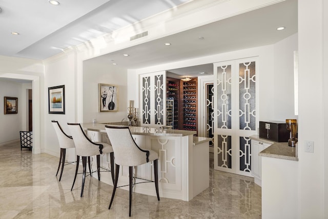 bar featuring light stone counters and white cabinets