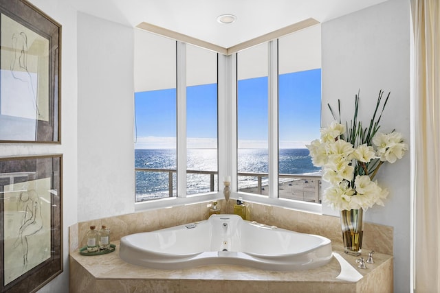 bathroom featuring tiled bath and a water view