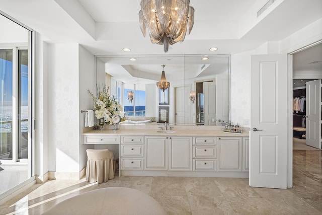 bathroom featuring a healthy amount of sunlight, a tray ceiling, a chandelier, and vanity