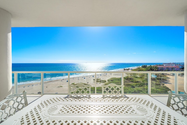 balcony with a water view and a view of the beach