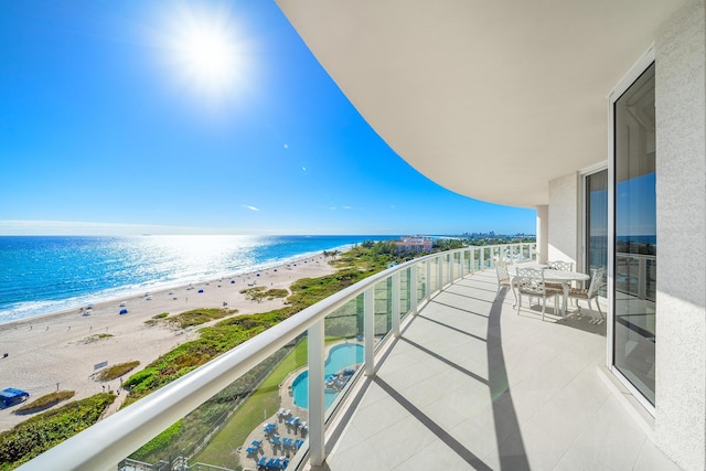 balcony featuring a view of the beach and a water view