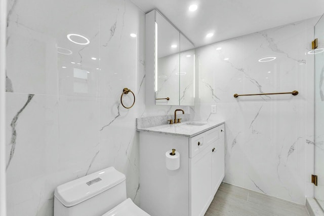 bathroom with toilet, tile walls, and vanity