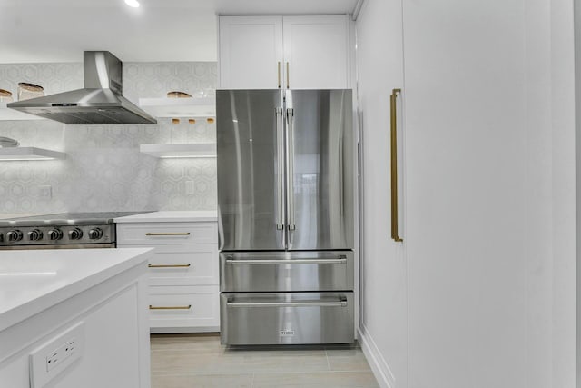 kitchen featuring white cabinets, backsplash, wall chimney range hood, and stainless steel appliances