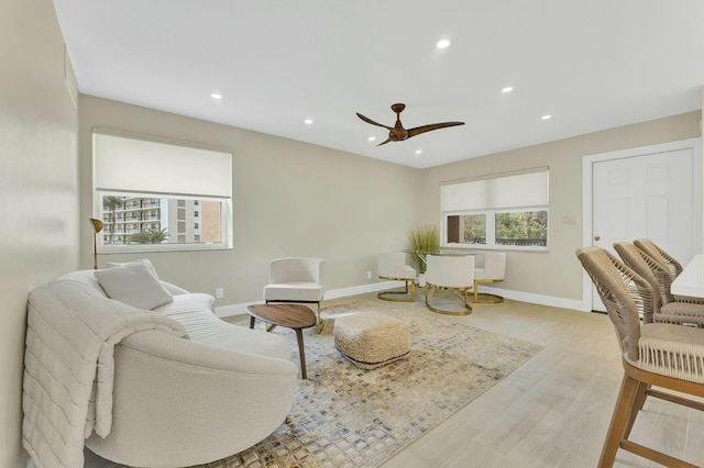 living room featuring light wood-type flooring, ceiling fan, and plenty of natural light