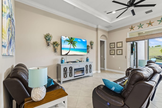 tiled living room with ceiling fan, ornamental molding, and a tray ceiling