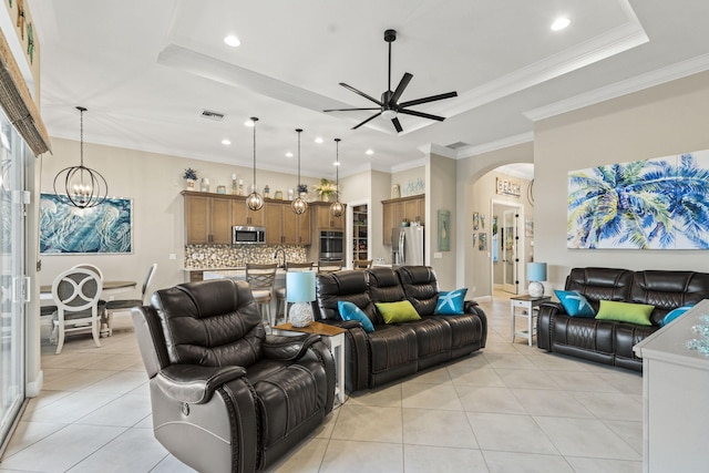 living room featuring light tile patterned flooring, ornamental molding, and a tray ceiling