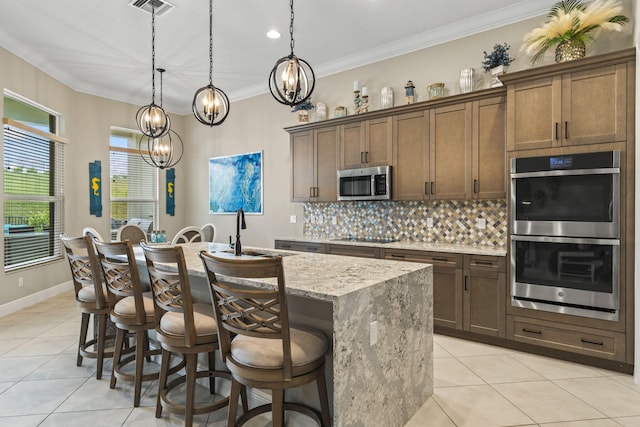 kitchen featuring sink, light stone counters, a center island with sink, pendant lighting, and stainless steel appliances