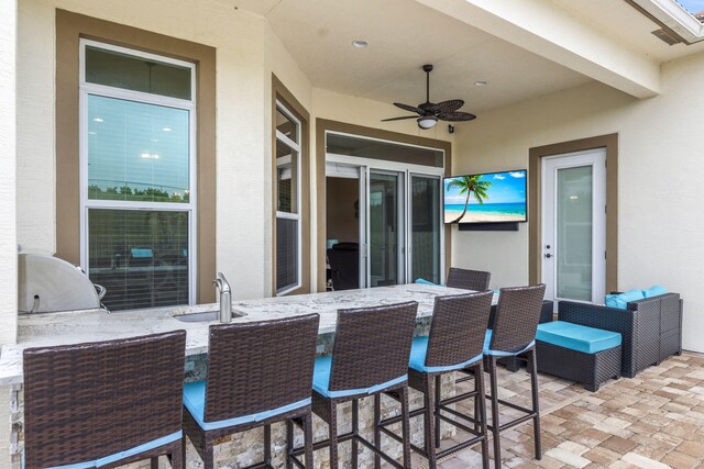 view of patio / terrace with area for grilling, ceiling fan, and an outdoor wet bar