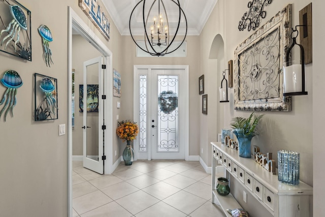 foyer with ornamental molding, a chandelier, and light tile patterned floors