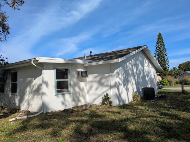 view of side of property with an AC wall unit, central AC unit, and a yard