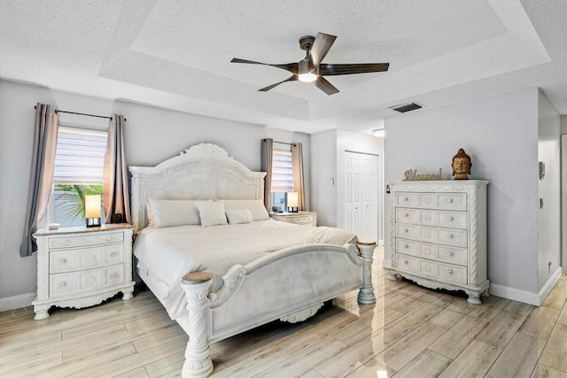 bedroom with a closet, ceiling fan, and a tray ceiling