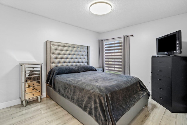 bedroom with light hardwood / wood-style floors and a textured ceiling