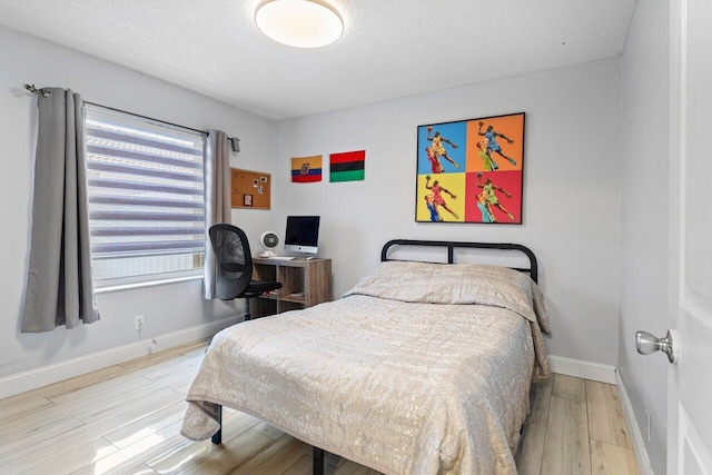 bedroom with light hardwood / wood-style floors and a textured ceiling