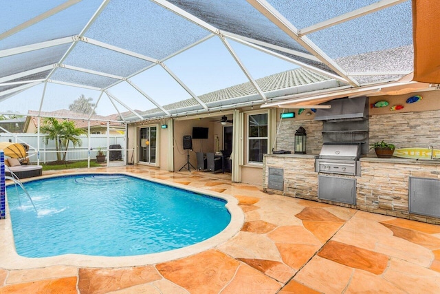 view of pool with exterior kitchen, glass enclosure, pool water feature, a patio, and grilling area