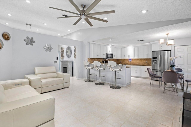 living room featuring ceiling fan, a textured ceiling, and lofted ceiling