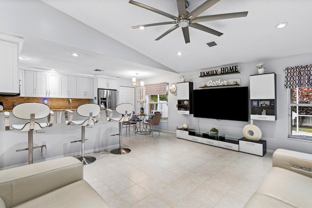 living room with ceiling fan, a textured ceiling, and vaulted ceiling