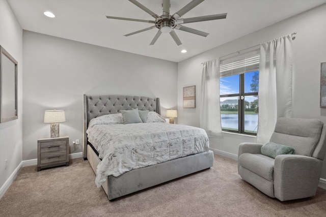 carpeted bedroom featuring ceiling fan and a water view