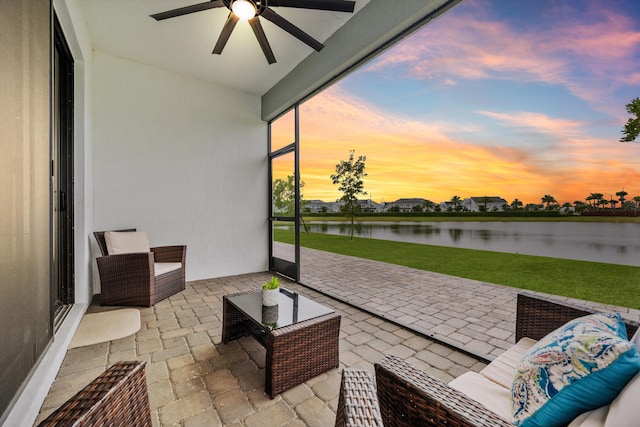 sunroom / solarium with ceiling fan and a water view