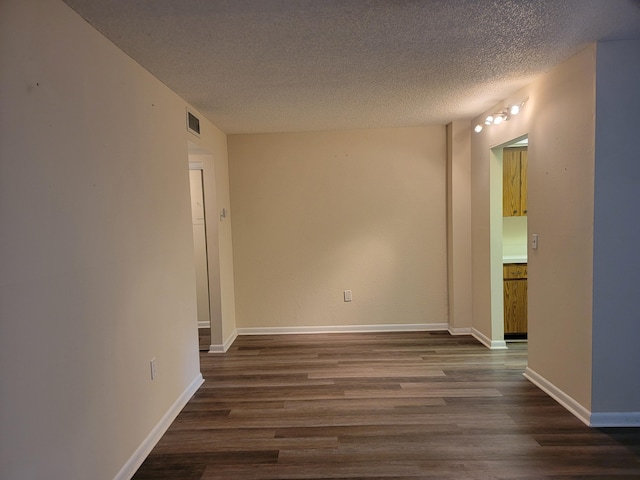 spare room featuring a textured ceiling and dark hardwood / wood-style floors