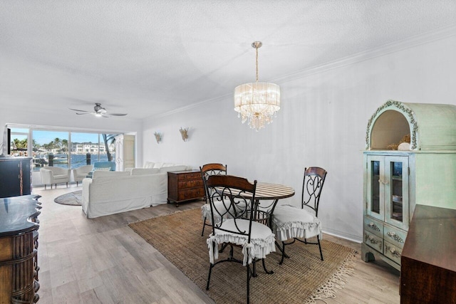 dining area featuring ceiling fan with notable chandelier, a textured ceiling, light hardwood / wood-style flooring, and ornamental molding