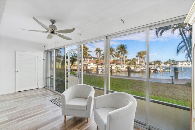 sunroom / solarium featuring ceiling fan and a water view