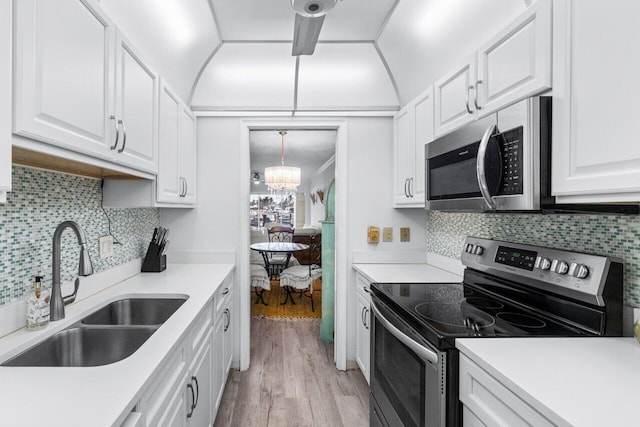 kitchen with white cabinets, appliances with stainless steel finishes, sink, and a chandelier