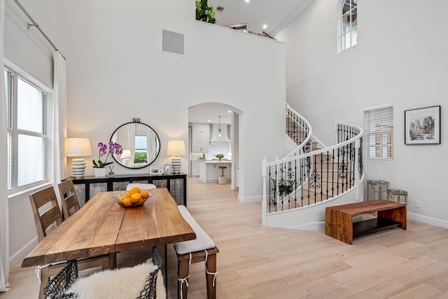 dining space featuring a high ceiling, plenty of natural light, and light wood-type flooring