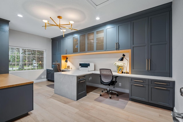 office space featuring built in desk, a notable chandelier, and light hardwood / wood-style flooring