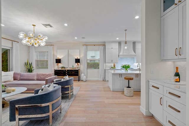 living room featuring a chandelier, sink, and light hardwood / wood-style flooring