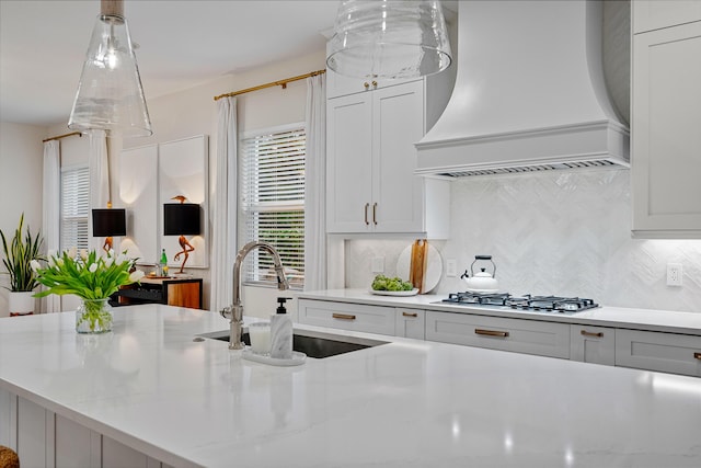 kitchen featuring premium range hood, sink, tasteful backsplash, and white cabinets