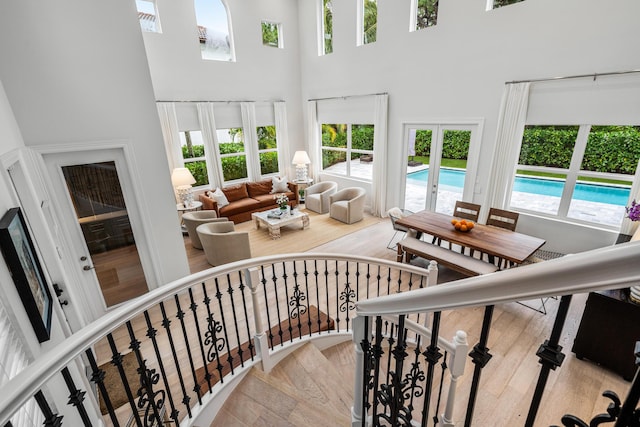 stairs featuring french doors, a towering ceiling, and hardwood / wood-style flooring