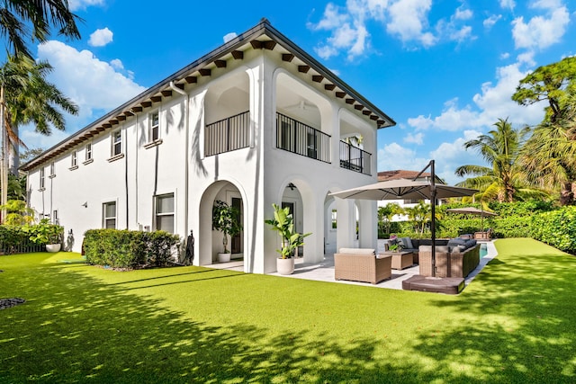 back of house with a yard, outdoor lounge area, a patio, and a balcony