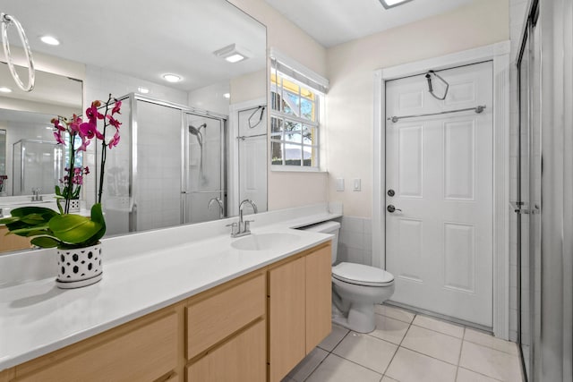 bathroom featuring toilet, vanity, tile patterned flooring, and a shower with door