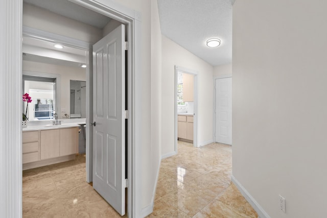 corridor featuring sink, a wealth of natural light, a textured ceiling, and vaulted ceiling