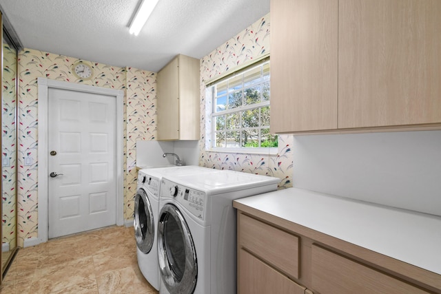 clothes washing area featuring cabinets, a textured ceiling, and separate washer and dryer