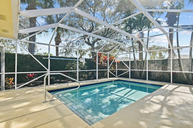 view of pool with glass enclosure and a patio area