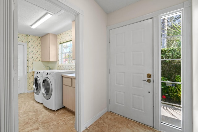 laundry room with a healthy amount of sunlight, washer and clothes dryer, a textured ceiling, and cabinets