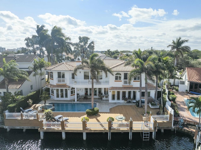 rear view of house featuring a pool side deck with water view, a patio area, and a balcony