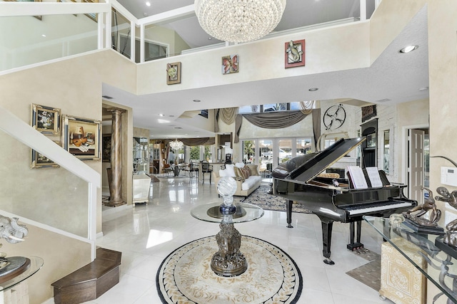 tiled entryway with a towering ceiling, crown molding, a chandelier, and decorative columns