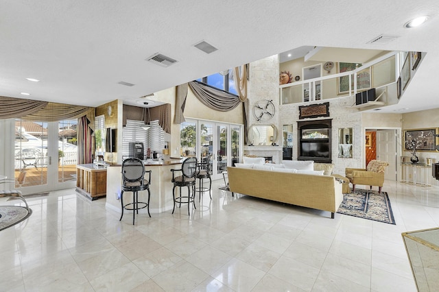 living room featuring french doors, a towering ceiling, a large fireplace, and a textured ceiling