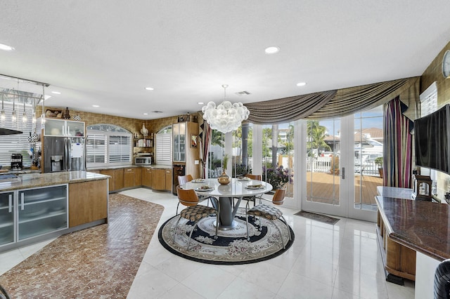 kitchen with decorative light fixtures, appliances with stainless steel finishes, a textured ceiling, light tile patterned floors, and stone countertops