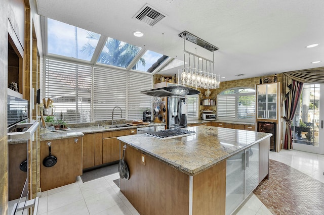 kitchen with decorative light fixtures, a center island, sink, a skylight, and light tile patterned floors