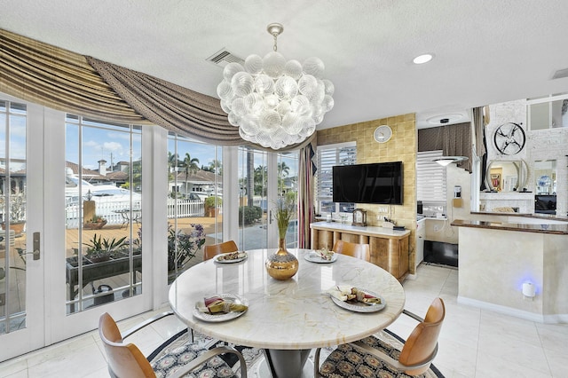 dining room with a textured ceiling, light tile patterned floors, a notable chandelier, and a healthy amount of sunlight