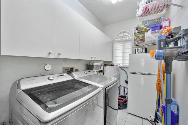 laundry area with cabinets, separate washer and dryer, light tile patterned floors, and a textured ceiling