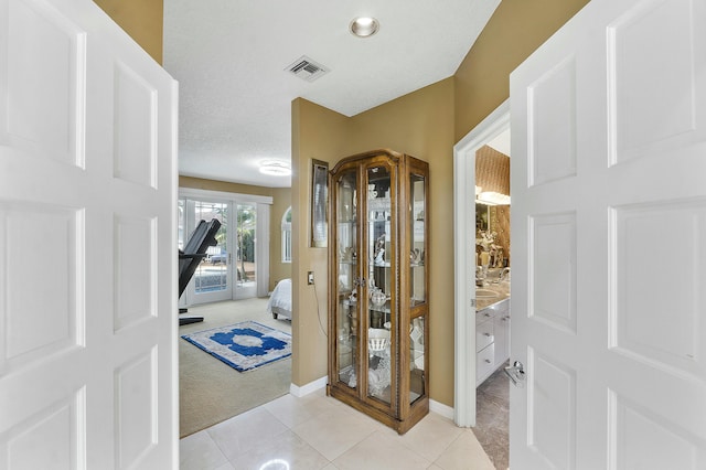 carpeted entrance foyer featuring a textured ceiling and french doors