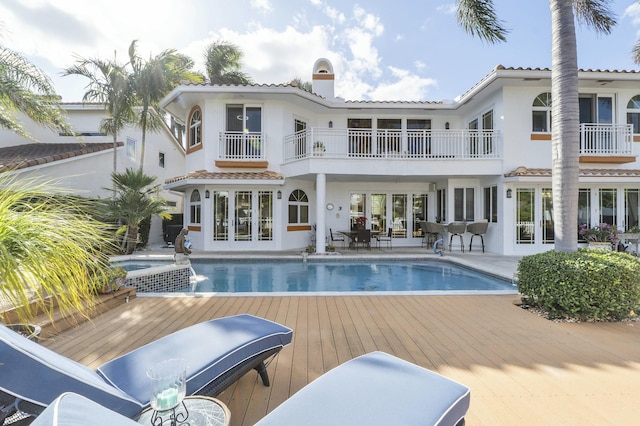 rear view of property with a patio area, french doors, a pool side deck, and a balcony