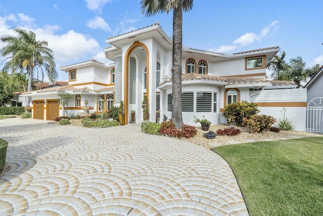 mediterranean / spanish-style home featuring a front lawn and a garage