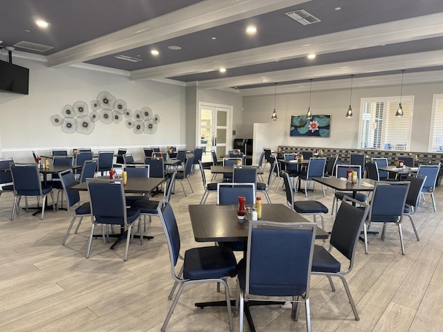 dining space with light hardwood / wood-style floors and beamed ceiling